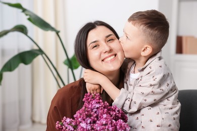 Photo of Mother and her son with bouquet of lilac flowers at home