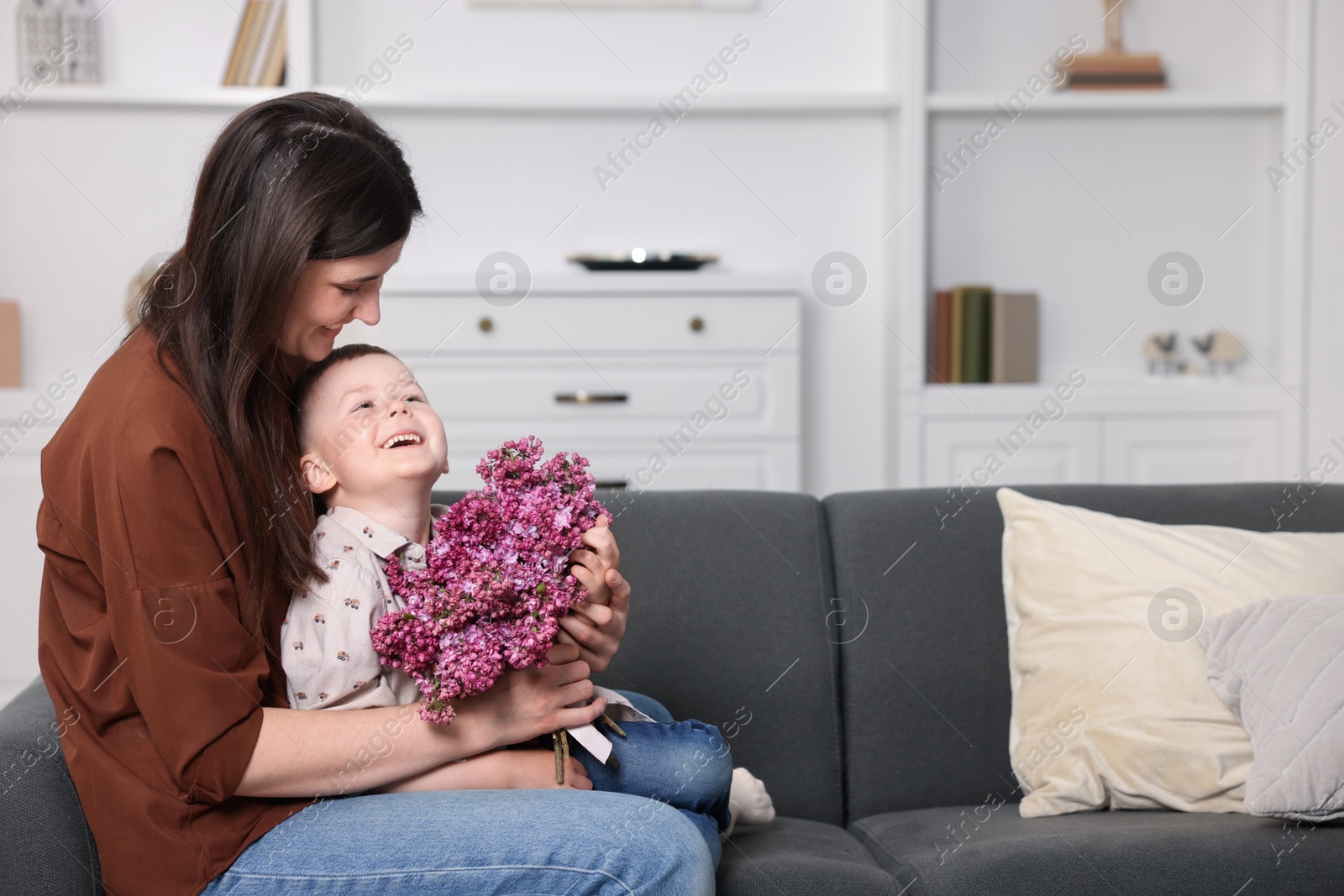 Mother and her son with bouquet of lilac flowers at home, space for text Photo of Mother and her son with bouquet of lilac flowers at home, space for text