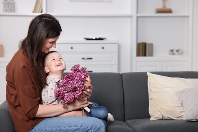 Photo of Mother and her son with bouquet of lilac flowers at home, space for text