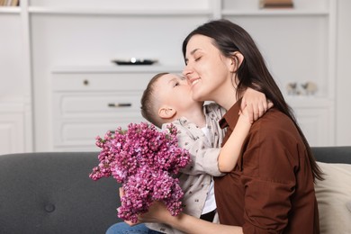 Photo of Mother and her son with bouquet of lilac flowers at home, space for text
