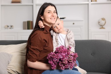 Photo of Mother and her son with bouquet of lilac flowers at home
