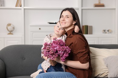 Photo of Mother and her son with bouquet of lilac flowers at home