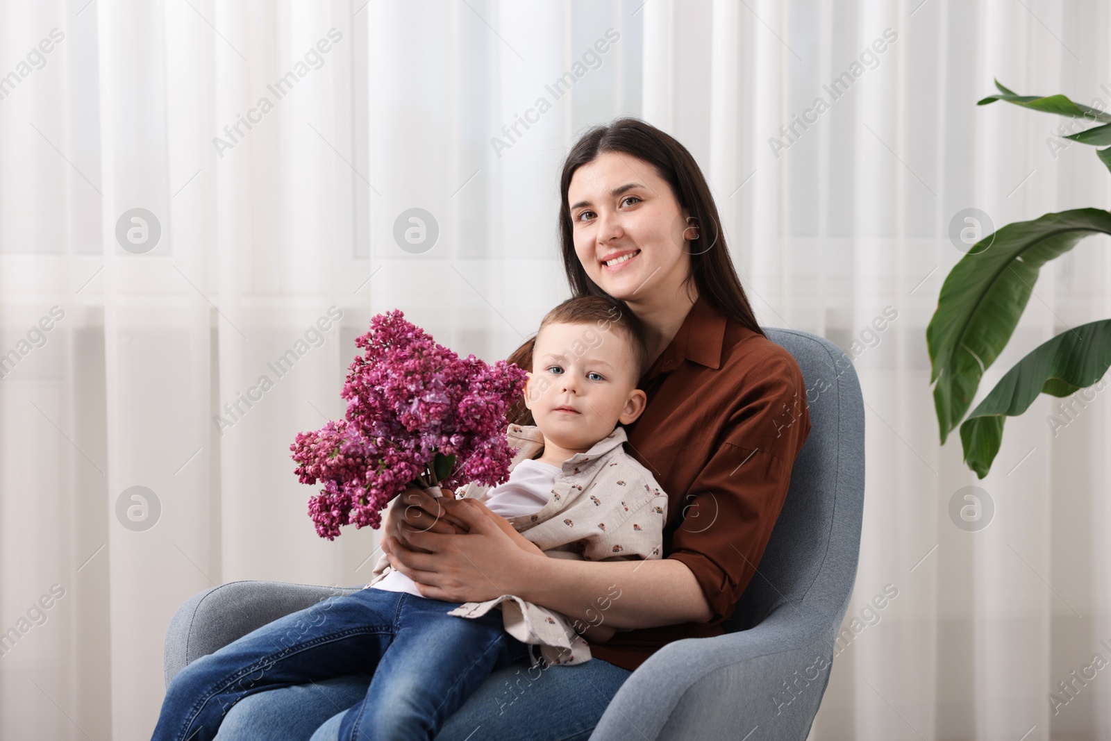 Mother and her son with bouquet of lilac flowers at home Photo of Mother and her son with bouquet of lilac flowers at home
