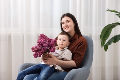 Photo of Mother and her son with bouquet of lilac flowers at home