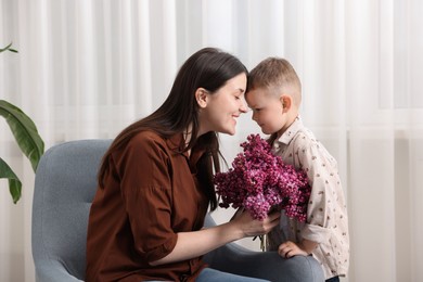 Photo of Mother and her son with bouquet of lilac flowers at home