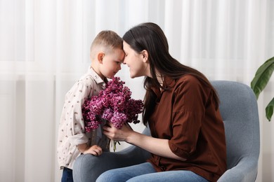 Photo of Mother and her son with bouquet of lilac flowers at home