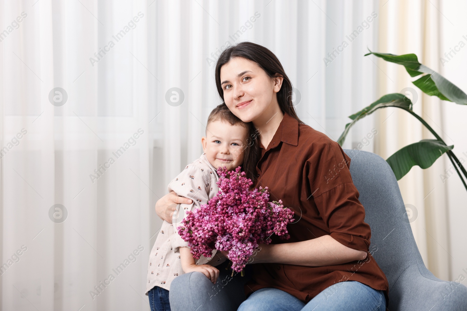 Mother and her son with bouquet of lilac flowers at home, space for text Photo of Mother and her son with bouquet of lilac flowers at home, space for text