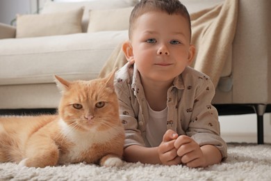 Photo of Little boy with his cute ginger cat at home
