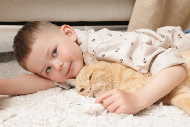 Photo of Little boy with his cute ginger cat at home