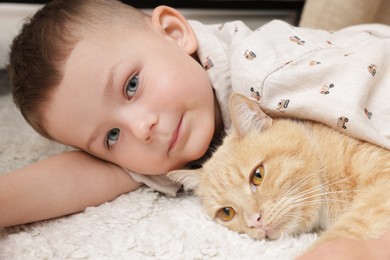 Photo of Little boy with his cute ginger cat at home