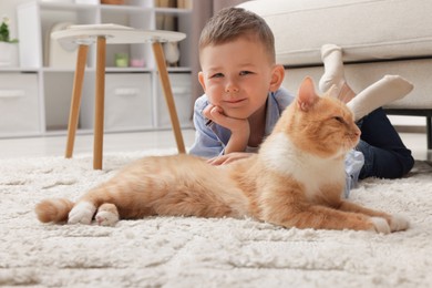 Photo of Little boy with his cute ginger cat at home