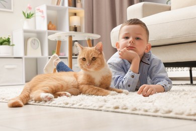 Photo of Little boy with his cute ginger cat at home