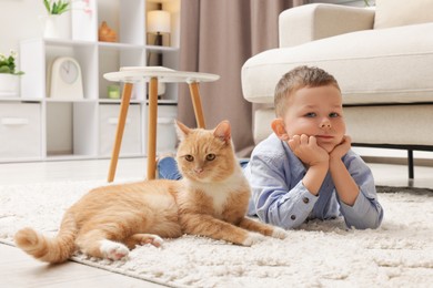 Photo of Little boy with his cute ginger cat at home