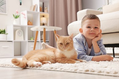 Photo of Little boy with his cute ginger cat at home