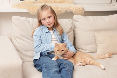 Photo of Little girl with her cute ginger cat at home