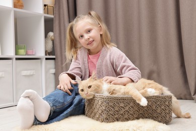 Photo of Little girl with her cute ginger cat at home