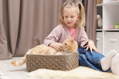 Photo of Little girl with her cute ginger cat at home
