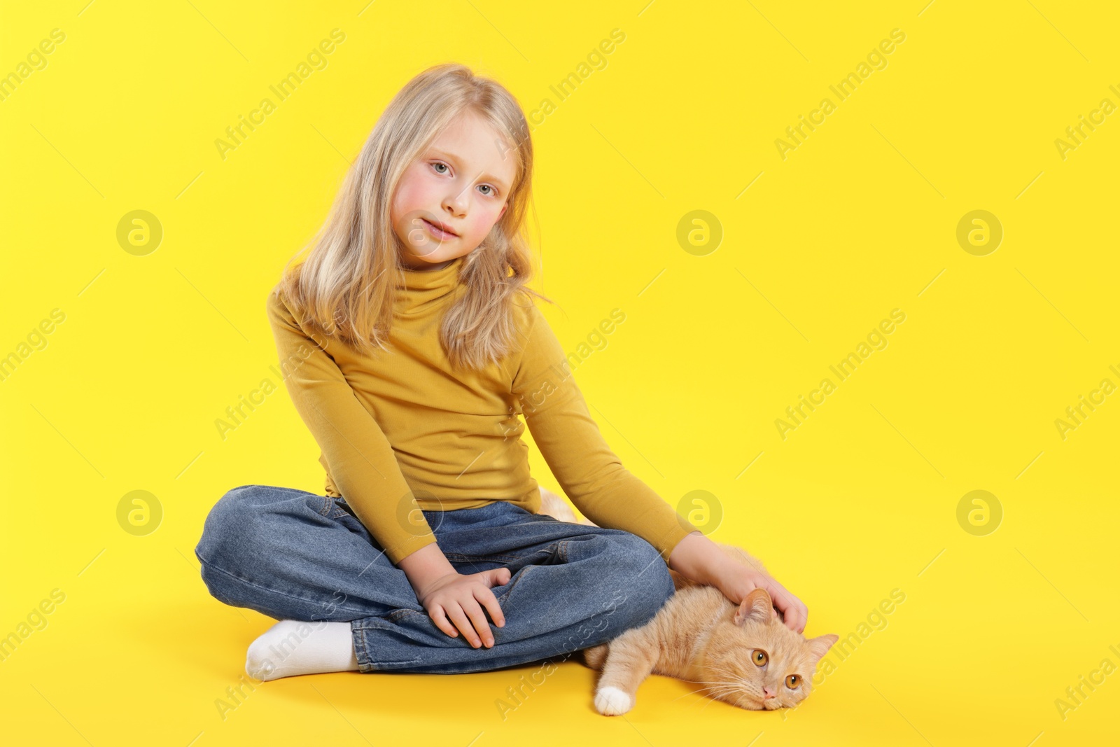 Little girl with her cute ginger cat on yellow background, space for text Photo of Little girl with her cute ginger cat on yellow background, space for text