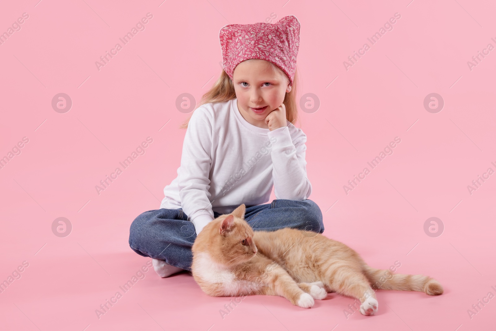 Little girl with her cute ginger cat on pink background Photo of Little girl with her cute ginger cat on pink background