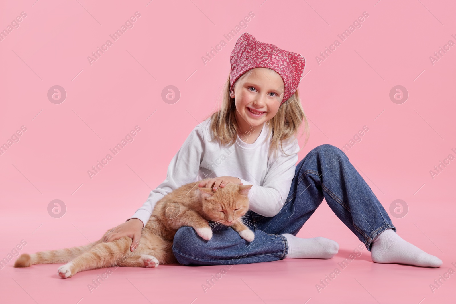 Little girl with her cute ginger cat on pink background Photo of Little girl with her cute ginger cat on pink background