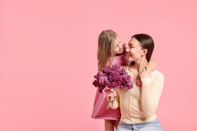 Photo of Mother and her daughter with bouquet of lilac flowers on pink background, space for text