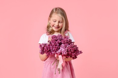 Photo of Little girl with bouquet of lilac flowers on pink background