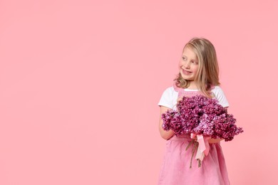 Photo of Little girl with bouquet of lilac flowers on pink background, space for text