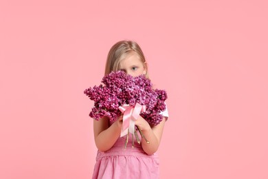 Photo of Little girl with bouquet of lilac flowers on pink background