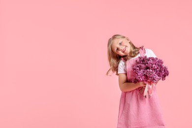Photo of Little girl with bouquet of lilac flowers on pink background, space for text