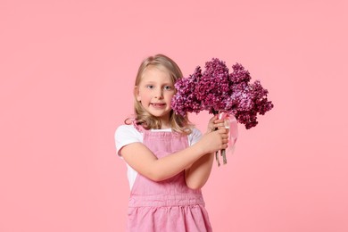 Photo of Little girl with bouquet of lilac flowers on pink background