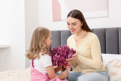 Photo of Mother and her daughter with bouquet of lilac flowers at home