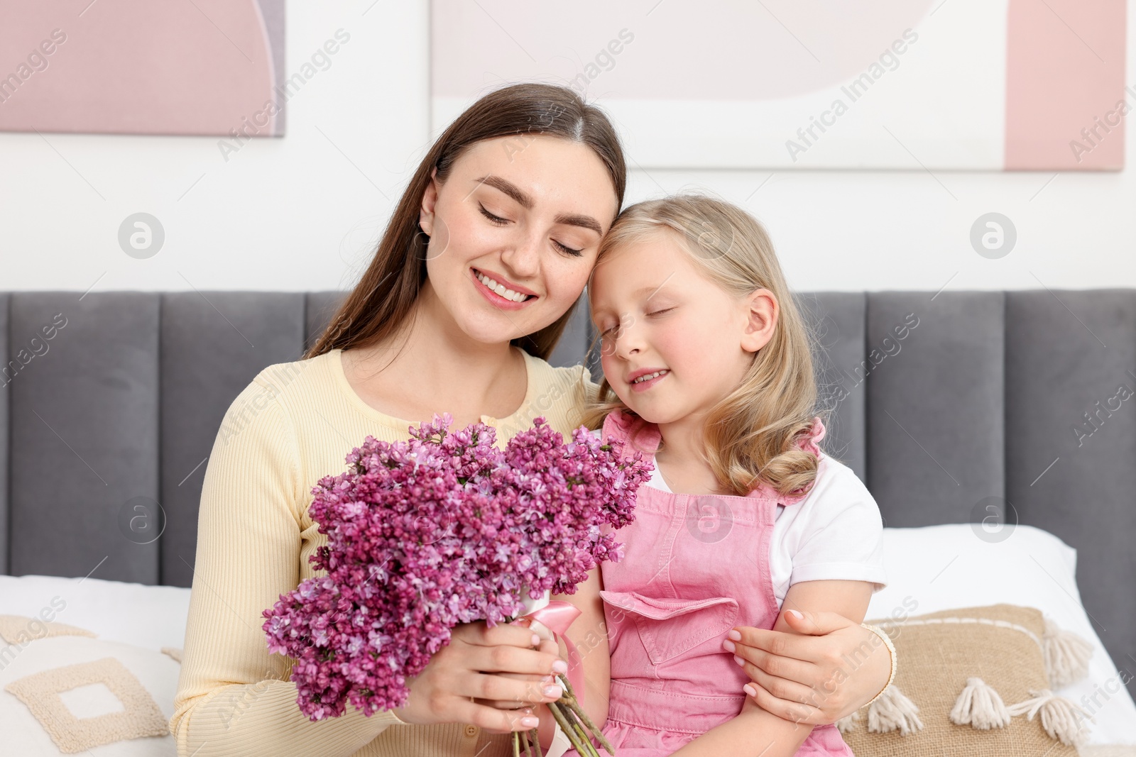 Mother and her daughter with bouquet of lilac flowers at home Photo of Mother and her daughter with bouquet of lilac flowers at home