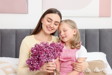 Photo of Mother and her daughter with bouquet of lilac flowers at home