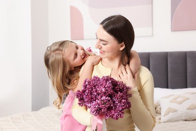 Photo of Mother and her daughter with bouquet of lilac flowers at home