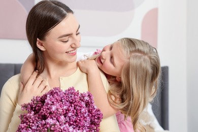 Photo of Mother and her daughter with bouquet of lilac flowers at home