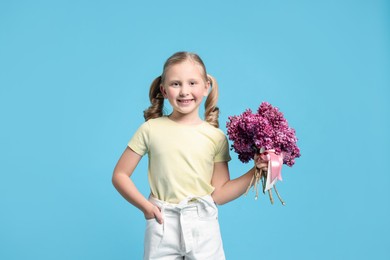 Photo of Little girl with bouquet of lilac flowers on light blue background