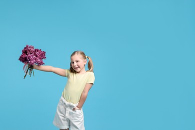 Photo of Little girl with bouquet of lilac flowers on light blue background, space for text