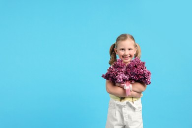 Photo of Little girl with bouquet of lilac flowers on light blue background, space for text