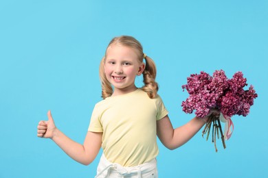 Photo of Little girl with bouquet of lilac flowers showing thumbs up on light blue background