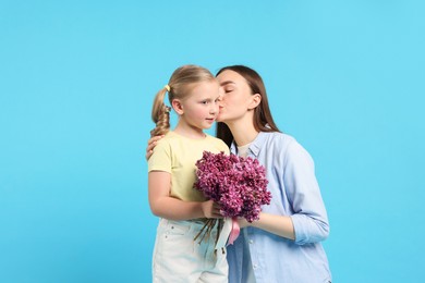 Photo of Mother and her daughter with bouquet of lilac flowers on light blue background