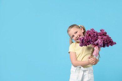 Photo of Little girl with bouquet of lilac flowers on light blue background, space for text