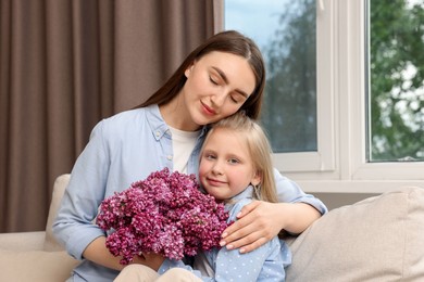 Photo of Mother and her daughter with bouquet of lilac flowers at home