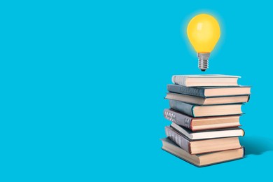 Image of Idea and knowledge. Light bulb in air over stack of books on light blue background, space for text