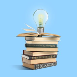 Image of Light bulb on stack of books against light blue background. Idea and knowledge