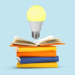 Image of Light bulb in air over stack of books on pastel blue background. Idea and knowledge