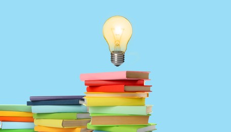Image of Idea and knowledge. Light bulb in air over books on light blue background. Banner design