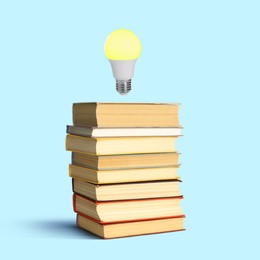 Image of Light bulb in air over stack of books on pastel blue background. Idea and knowledge