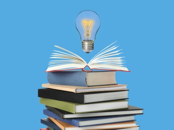 Image of Light bulb in air over stack of books on light blue background. Idea and knowledge