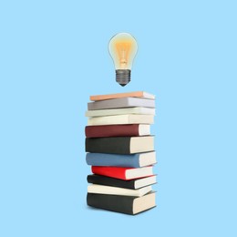 Image of Light bulb in air over stack of books against light blue background. Idea and knowledge