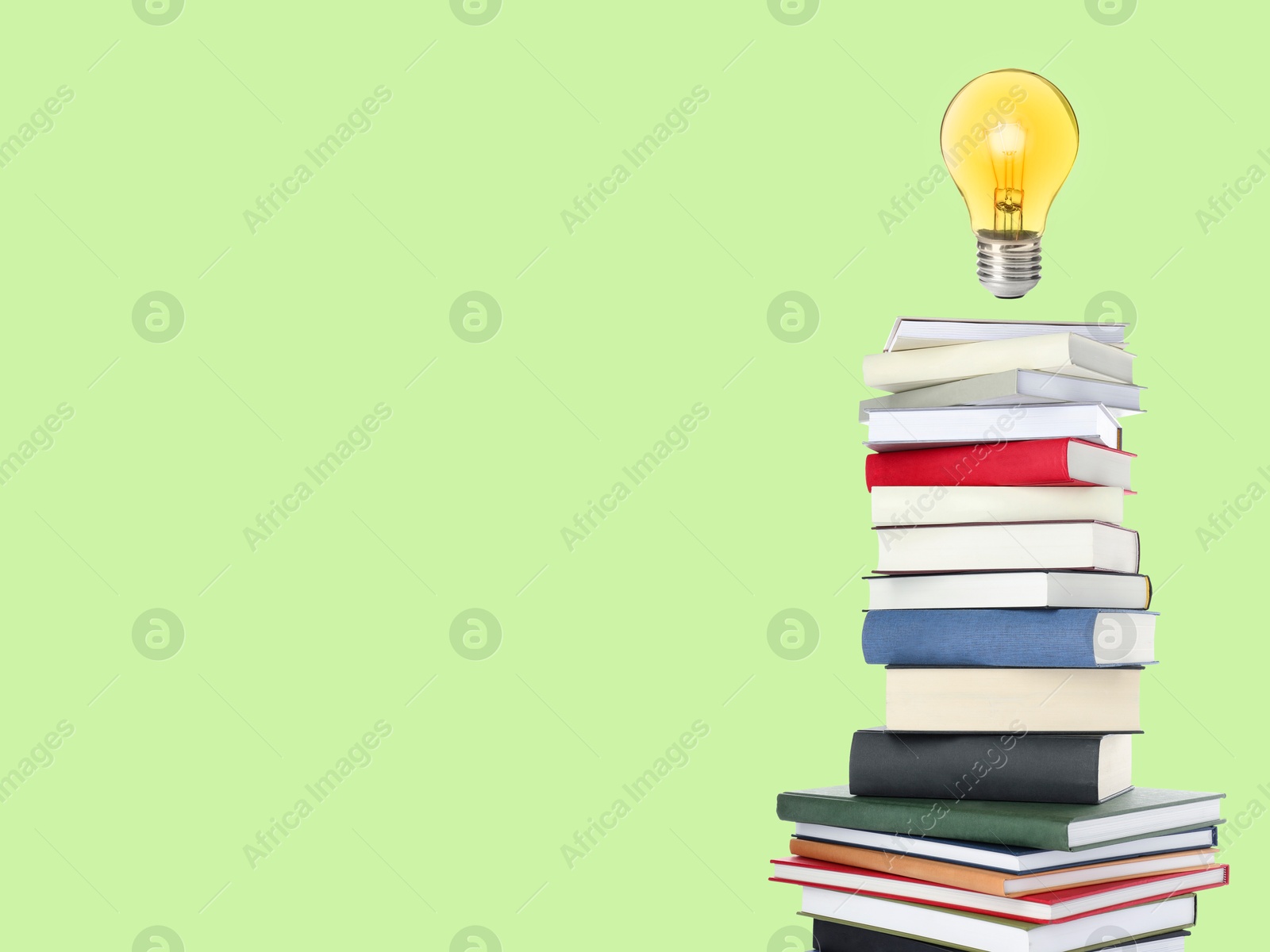 Light bulb in air over stack of books on light green background, space for text. Idea and knowledge Image of Light bulb in air over stack of books on light green background, space for text. Idea and knowledge